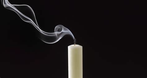 a single white candle with a dark background