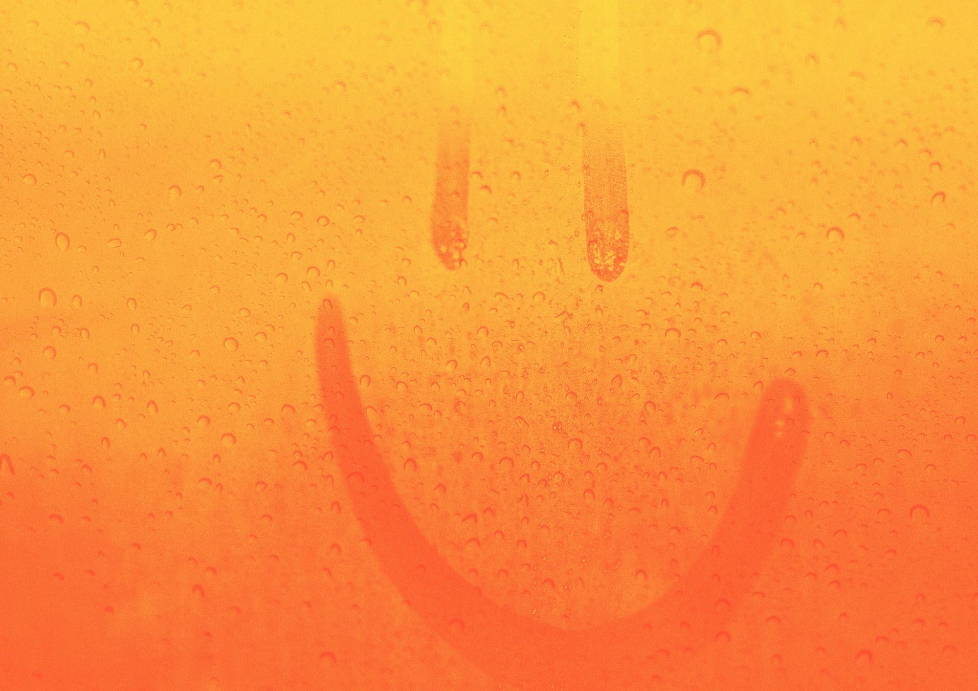 smiley face drawn into rain drops on a window